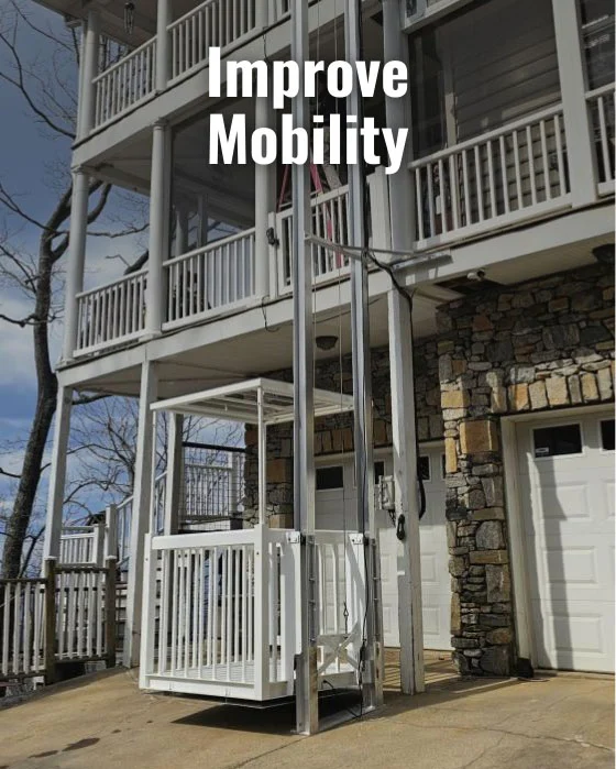Outdoor home elevator beside a multi-story house with stone facade, enhancing mobility. Text above reads "Improve Mobility."