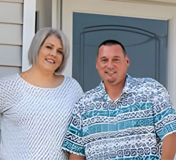 owners Smiling couple standing together outside a home entrance, next to a door.